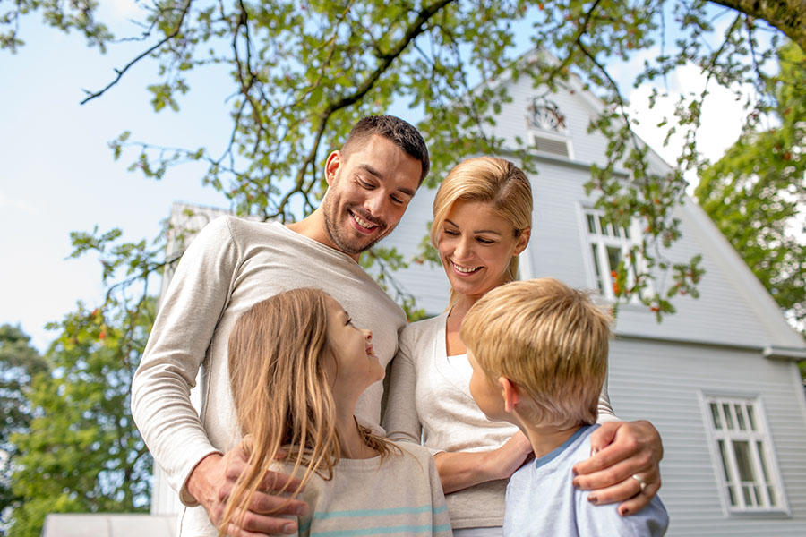 Personal Insurance - Portrait Of Happy Family With Two Kids Standing In Front Of Their House
